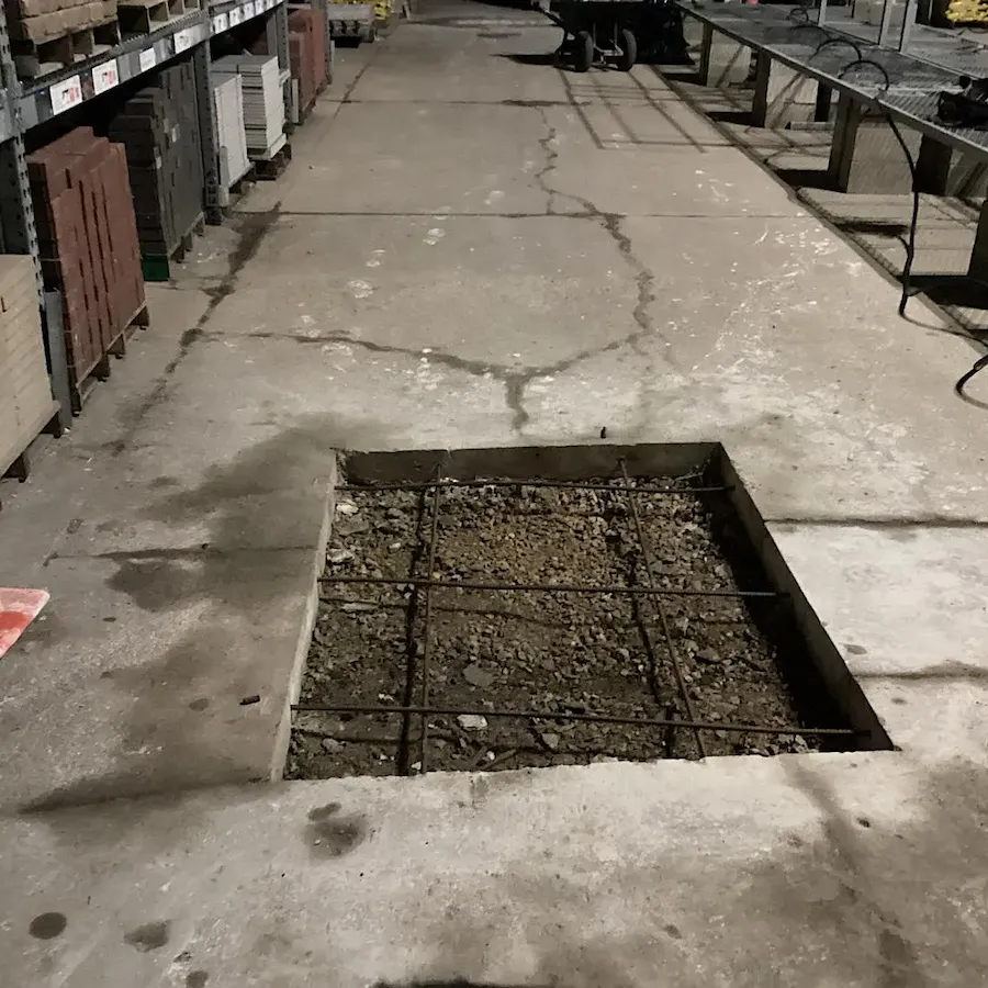 Installation of steel reinforcement mesh in concrete floor section for structural repair.