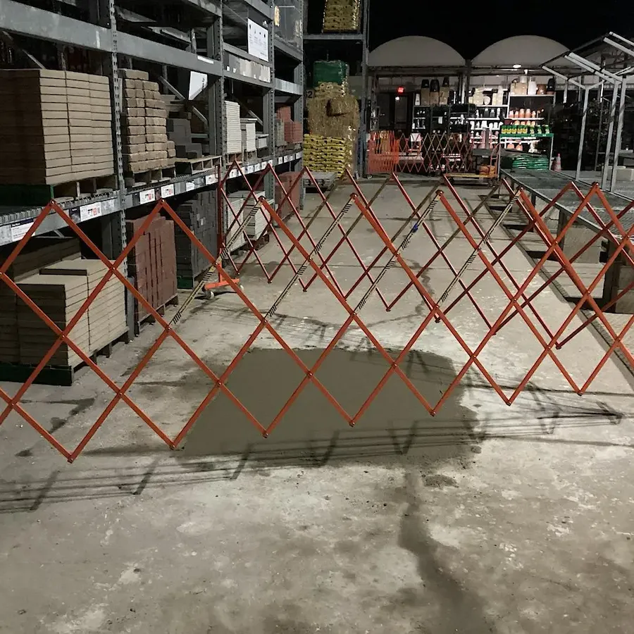 Final concrete floor repair phase: fresh pour, curing time, and work area cordoned off with safety barriers.